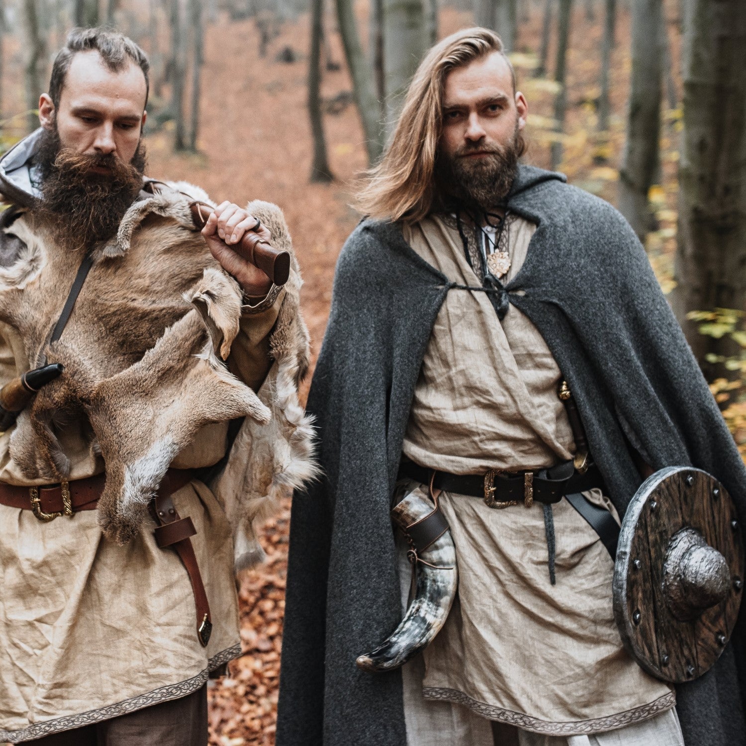 Two men in Viking attire standing in a forest setting.