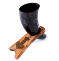 Black horn cup on a wooden stand with decorative emblem on a white background
