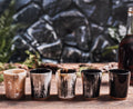 Set of five wooden shot glasses on a wooden surface with a stone wall background