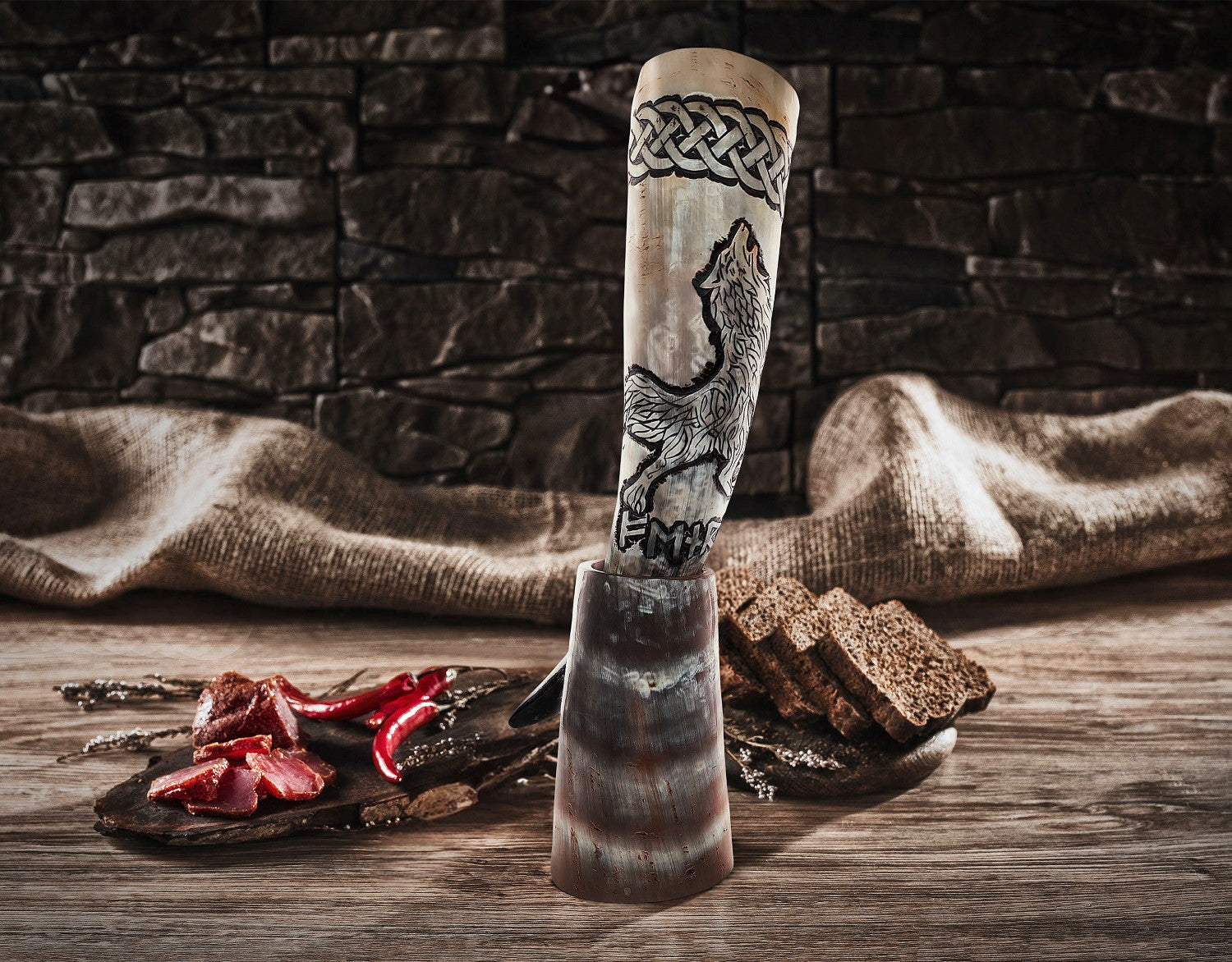 Decorative horn with carvings on a wooden surface with food items and a stone wall background