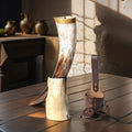 Decorative items including a large horn-shaped lamp and a wooden tool on a wooden surface.