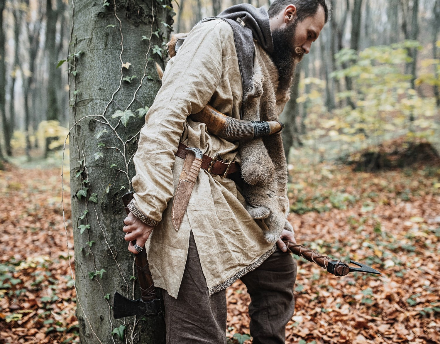 Man in medieval attire holding a weapon in a forest setting