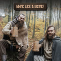 Two men in Viking attire sitting in a forest with 'Drink Like a Viking!' text above them.