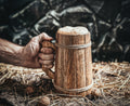 Hand holding a wooden mug with a dark background