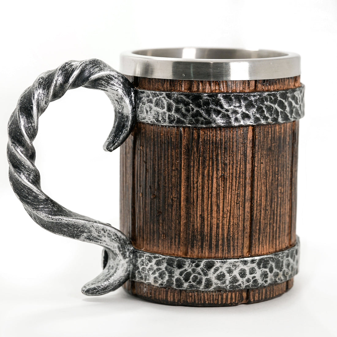 Wooden mug with metal handle and band on a wooden surface with blurred greenery in the background