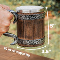 Wooden mug with metal handle and measurements, held by a hand against a blurred natural background.