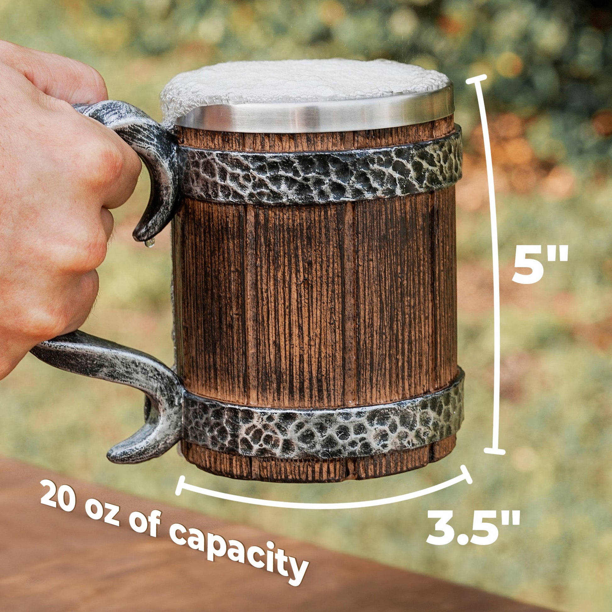Wooden mug with metal handle and measurements, held by a hand against a blurred natural background.